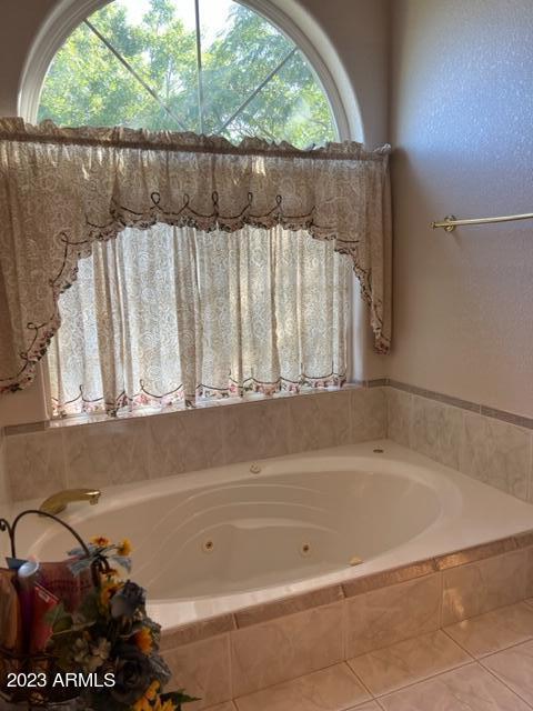 bathroom with a whirlpool tub, tile patterned flooring, and a wealth of natural light