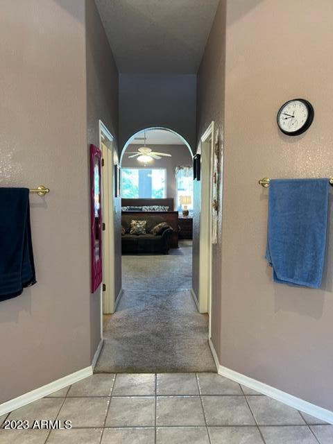 hall with arched walkways, light tile patterned floors, and baseboards