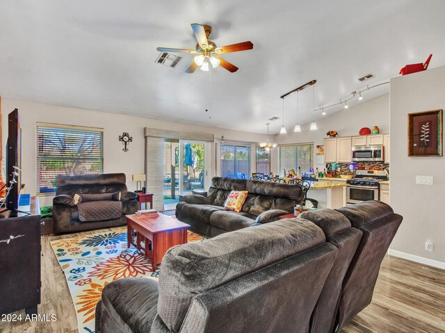 living room with plenty of natural light, vaulted ceiling, and light wood-type flooring