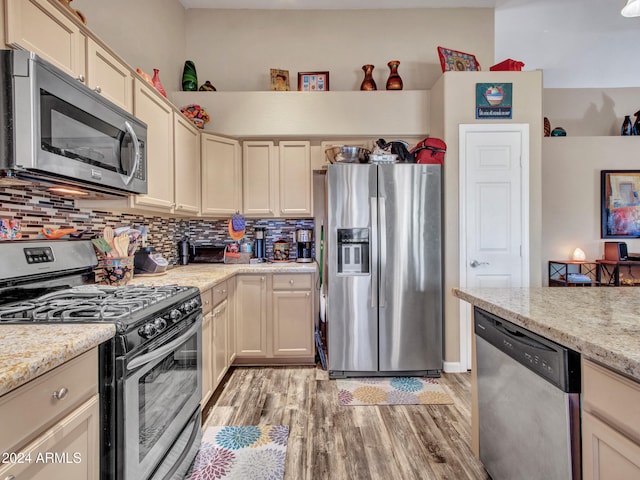 kitchen with appliances with stainless steel finishes, backsplash, and cream cabinetry