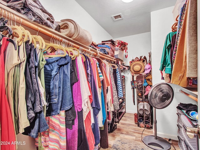 walk in closet with light hardwood / wood-style flooring