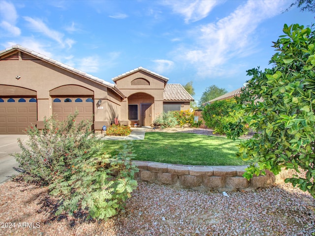 mediterranean / spanish house with a garage and a front lawn