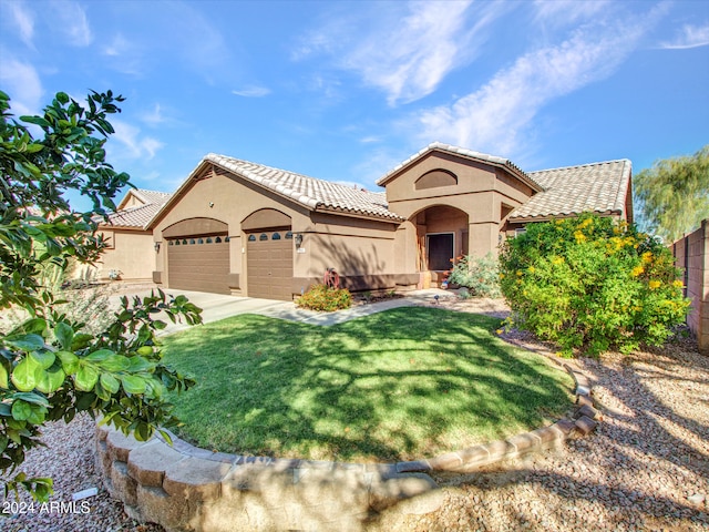 mediterranean / spanish house featuring a garage and a front lawn