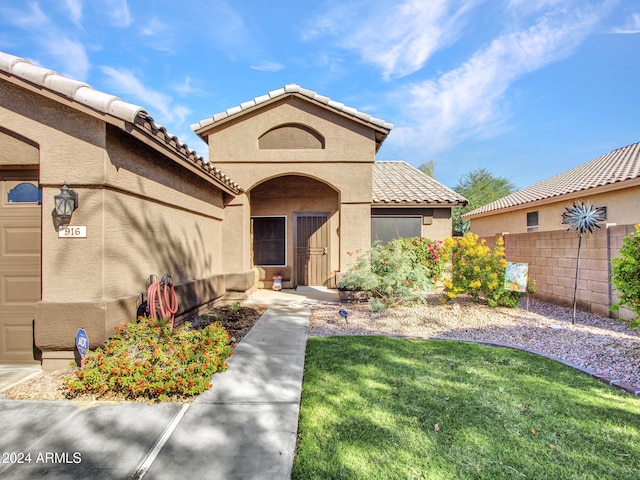 entrance to property featuring a garage and a lawn