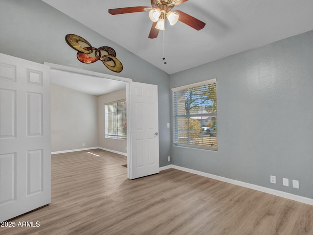 empty room with vaulted ceiling, ceiling fan, and light hardwood / wood-style floors