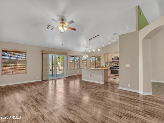 unfurnished living room featuring lofted ceiling, track lighting, ceiling fan, and light hardwood / wood-style flooring