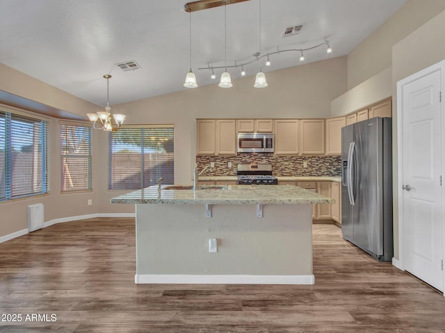 kitchen with sink, hanging light fixtures, stainless steel appliances, an island with sink, and vaulted ceiling