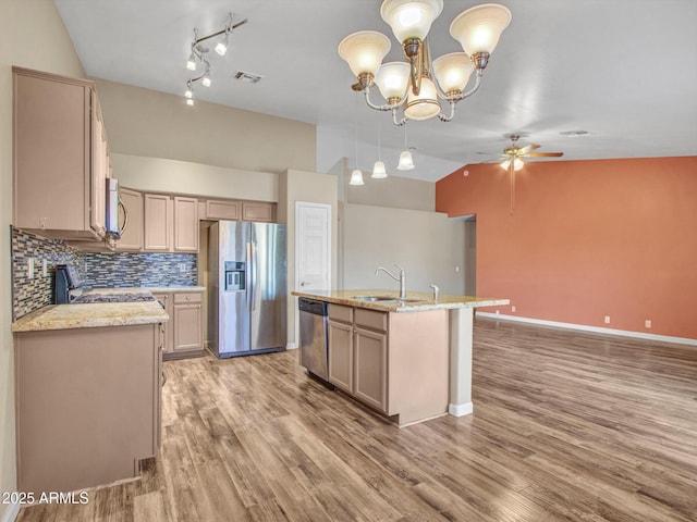 kitchen with light stone counters, sink, decorative light fixtures, and appliances with stainless steel finishes