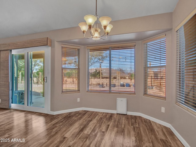 unfurnished dining area with an inviting chandelier and hardwood / wood-style floors