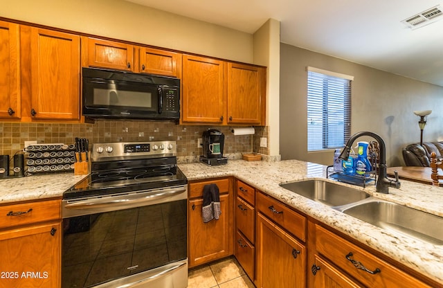 kitchen featuring stainless steel electric range oven, sink, backsplash, light tile patterned floors, and light stone counters