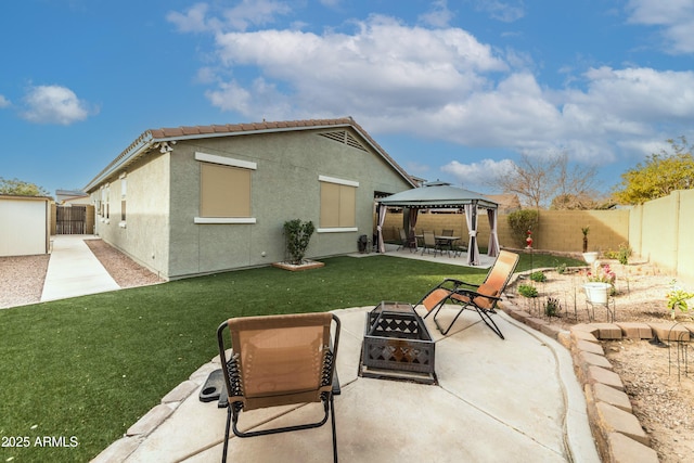 rear view of property featuring a patio area, a gazebo, a yard, and a fire pit