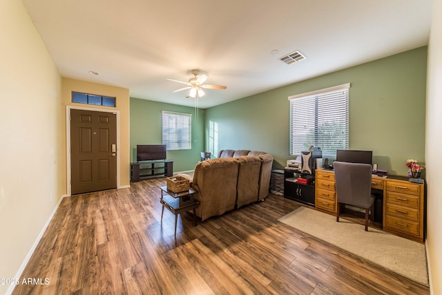 living room featuring ceiling fan, a wealth of natural light, and dark wood-type flooring