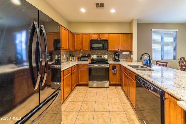 kitchen with black appliances, tasteful backsplash, light tile patterned floors, sink, and light stone counters