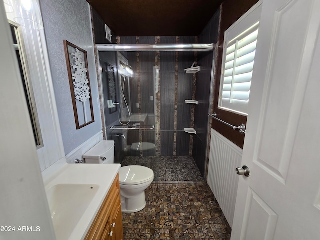 bathroom featuring vanity, a shower with shower door, and toilet