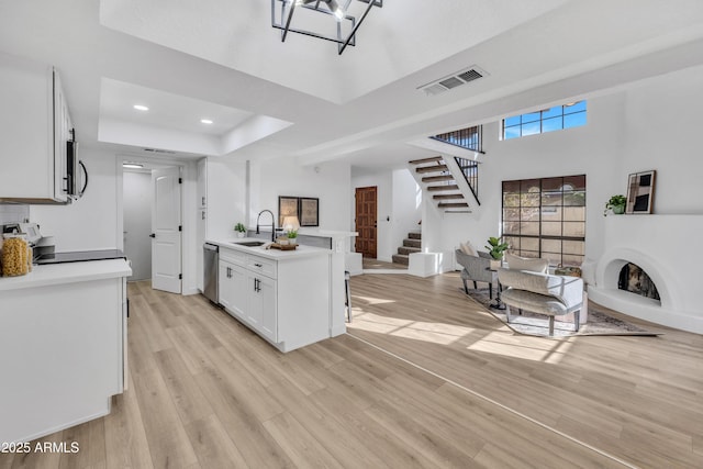 kitchen with visible vents, a raised ceiling, open floor plan, stainless steel appliances, and a sink