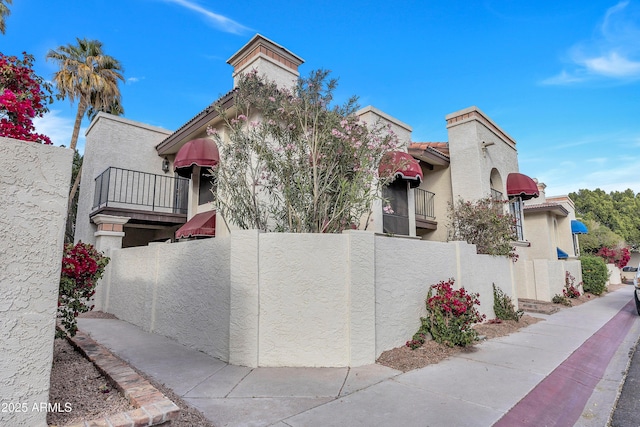 view of front facade with a balcony, fence private yard, and stucco siding