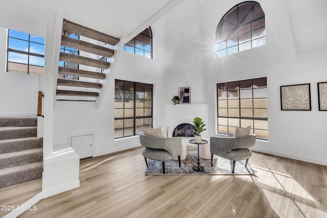 sitting room with stairs, wood finished floors, plenty of natural light, and a glass covered fireplace