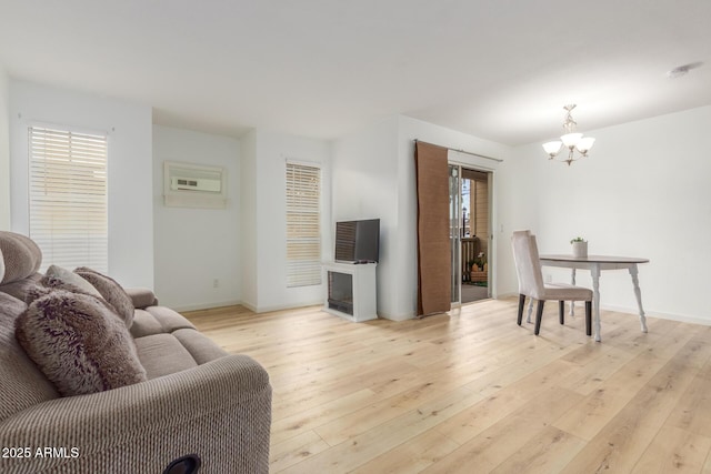 living area with light wood-type flooring, a fireplace, baseboards, and an inviting chandelier