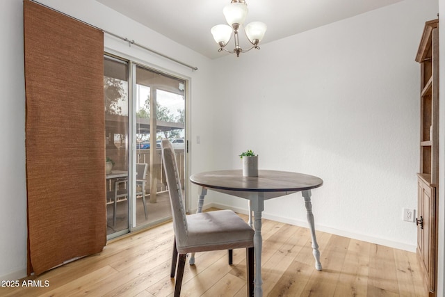 dining space featuring light wood finished floors, baseboards, and an inviting chandelier