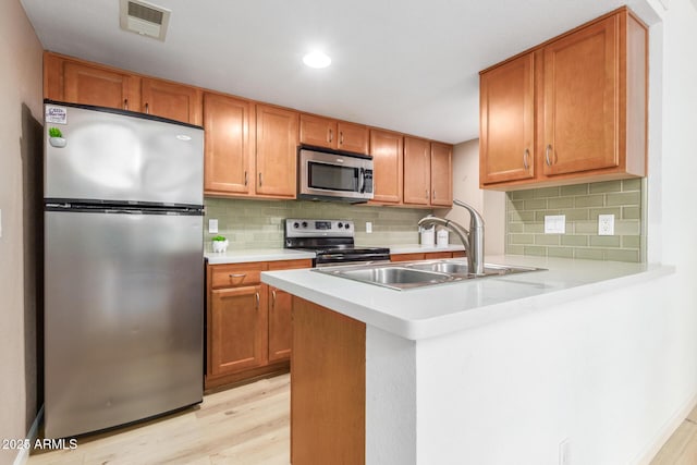 kitchen featuring visible vents, stainless steel appliances, light countertops, light wood-type flooring, and a sink