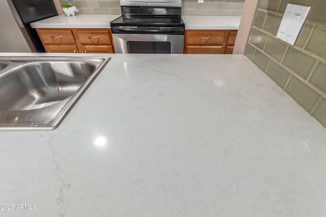 kitchen with brown cabinets, decorative backsplash, stainless steel appliances, and a sink