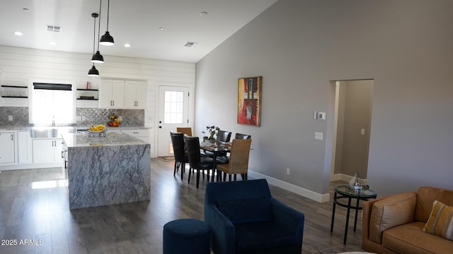 kitchen featuring hanging light fixtures, light stone countertops, dark hardwood / wood-style floors, and white cabinets