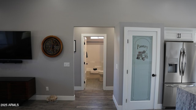 interior space with white cabinetry, stainless steel fridge with ice dispenser, light stone countertops, and dark hardwood / wood-style floors