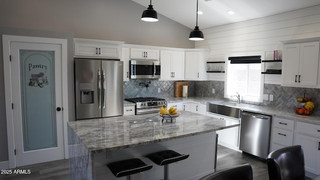 kitchen with pendant lighting, sink, appliances with stainless steel finishes, white cabinetry, and a kitchen island