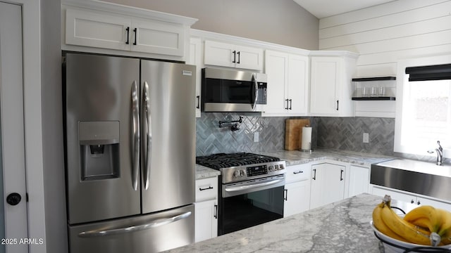 kitchen featuring light stone counters, stainless steel appliances, sink, and white cabinets