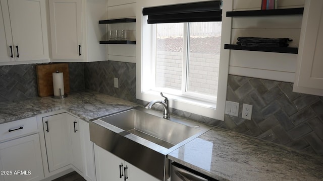 kitchen featuring sink, light stone countertops, and white cabinets