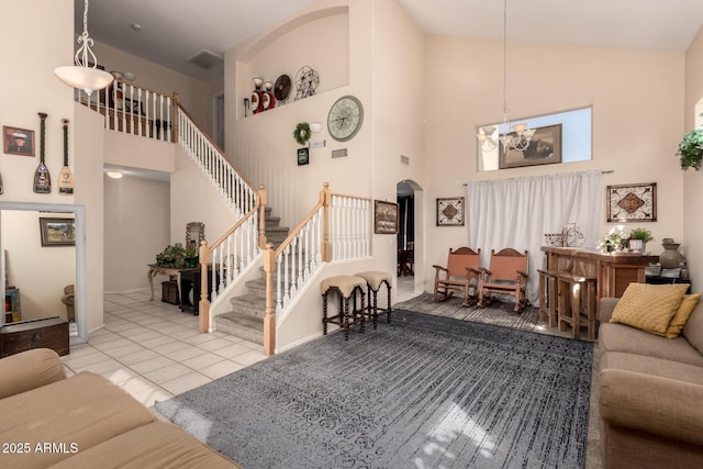 tiled living area with stairway, a chandelier, a towering ceiling, arched walkways, and visible vents
