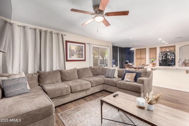 living room with light wood-style flooring and a ceiling fan