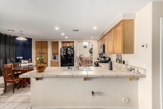 kitchen with stainless steel gas stove, a sink, visible vents, freestanding refrigerator, and a peninsula