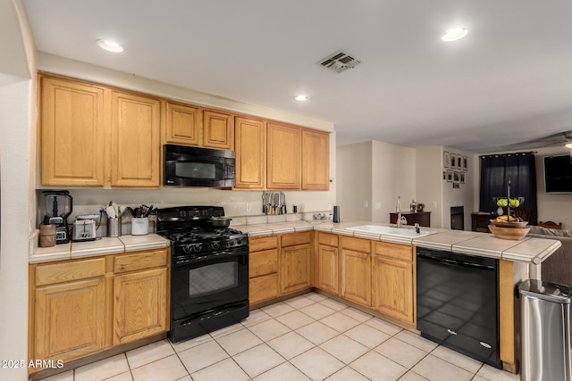 kitchen featuring a peninsula, open floor plan, tile countertops, visible vents, and black appliances