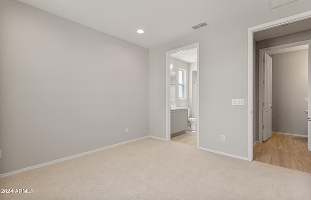 unfurnished bedroom featuring connected bathroom and light wood-type flooring