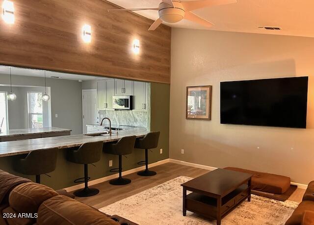 living room with wood-type flooring, ceiling fan, and sink