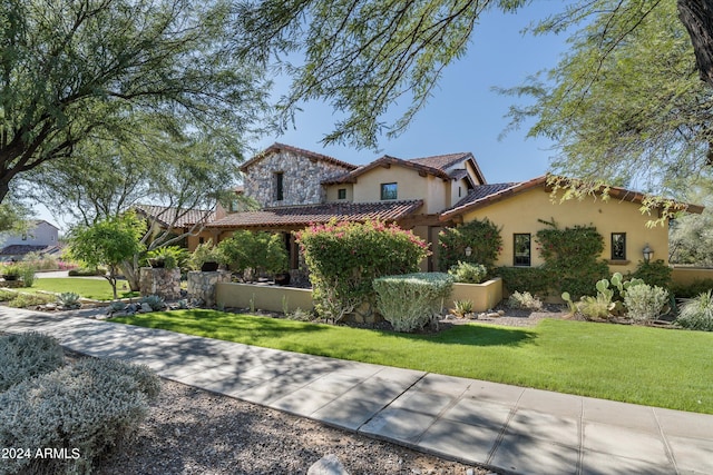 view of front of property with stucco siding, a tiled roof, and a front lawn