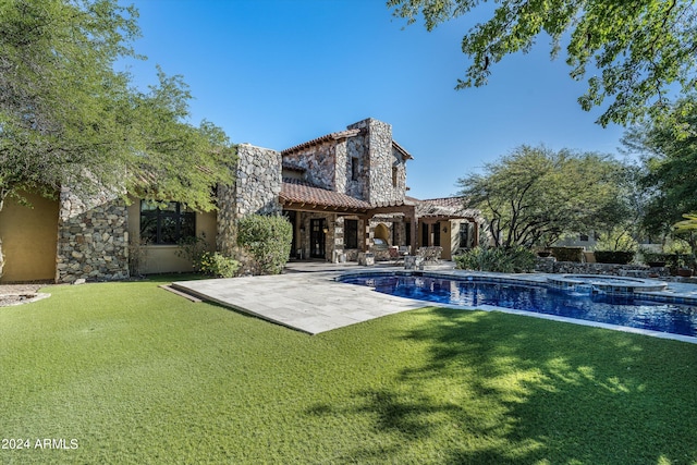 back of house featuring a swimming pool with hot tub, a patio area, and a lawn