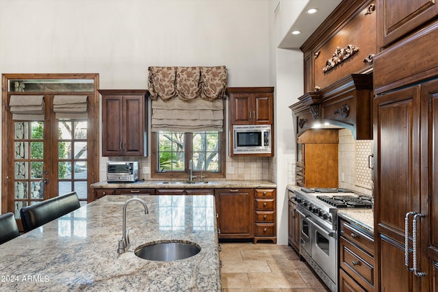 kitchen featuring french doors, stainless steel appliances, a wealth of natural light, sink, and light stone counters