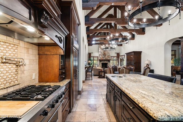 kitchen featuring a sink, stone tile floors, high end stainless steel range oven, arched walkways, and backsplash