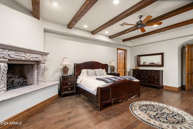 bedroom with beamed ceiling, dark wood-type flooring, and ceiling fan