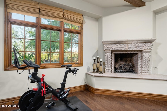 workout room featuring baseboards, a fireplace, and wood-type flooring