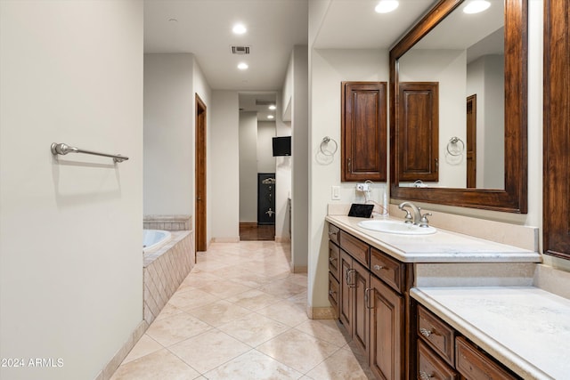 bathroom with vanity, tiled bath, and tile patterned flooring