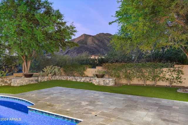 outdoor pool featuring a yard, a patio area, fence, and a mountain view