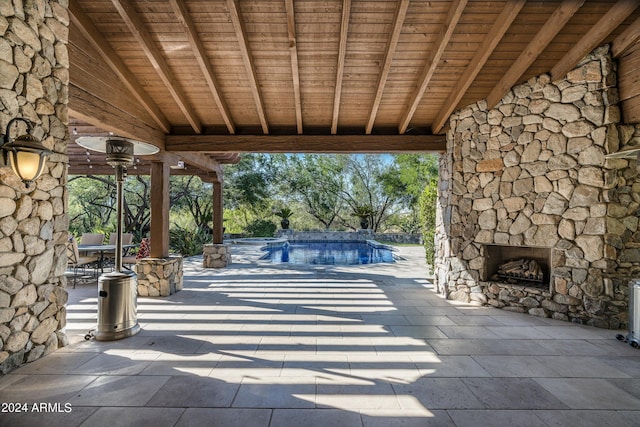 view of patio featuring an outdoor stone fireplace and an outdoor pool