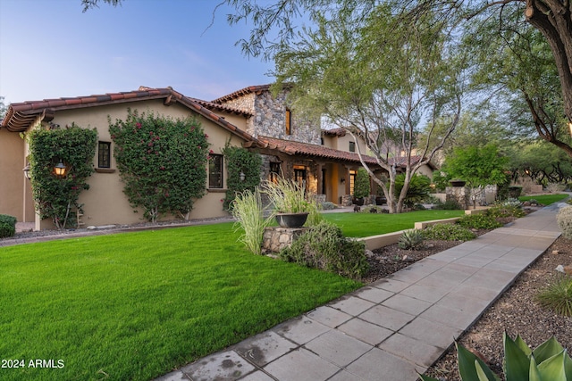 mediterranean / spanish-style home featuring stucco siding, a front lawn, and a tile roof