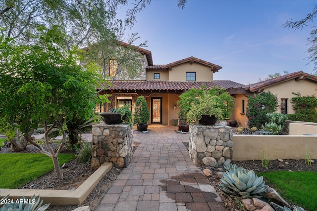 mediterranean / spanish-style house with a patio area, stucco siding, and a tiled roof