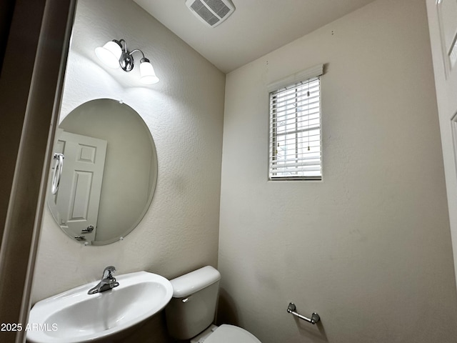 half bath featuring visible vents, vaulted ceiling, a sink, and toilet
