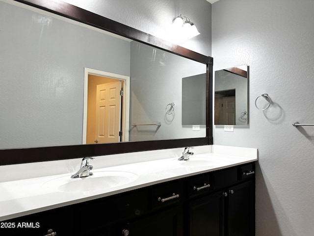 bathroom featuring double vanity, a sink, and a textured wall