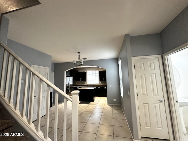 interior space with visible vents, baseboards, an inviting chandelier, stairs, and light tile patterned flooring